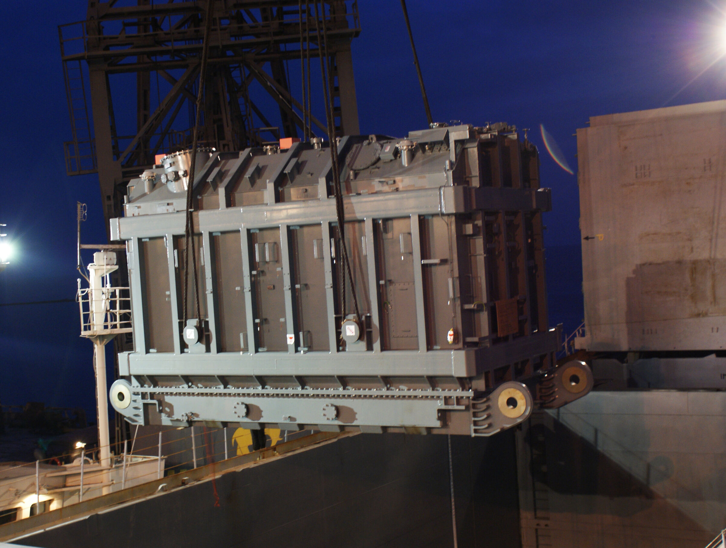 A power transformer lifted over the berth at dusk, port of Mariupol